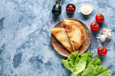 Lezzetli cheburekler, soslar ve mavi grunge masasında taze sebzeler.