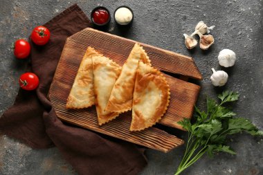 Lezzetli cheburekler, taze sebzeler ve siyah grunge masasında soslar.