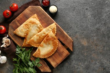 Lezzetli cheburekler, taze sebzeler ve siyah grunge masasında soslar.