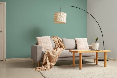 Gri kanepesi, ahşap masası ve lambası olan şık bir oturma odası.