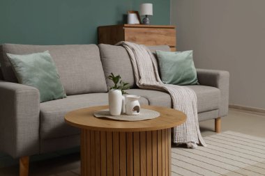 Oturma odasındaki vazolarda bitki dalları ve yanan mumlar var.