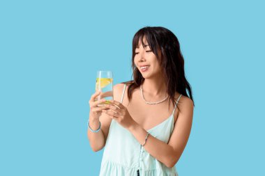 Mavi arka planda narenciye aşılamış genç Asyalı kadın.