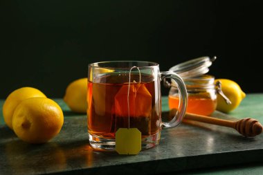 Koyu duvara karşı yeşil grunge masasında limonlu sıcak çay.