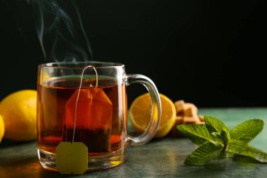 Yeşil grunge masasının üzerinde limonlu ve nane yapraklı bir fincan sıcak çay.