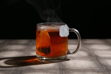 Koyu duvara karşı gri fayans üzerinde bir fincan sıcak çay