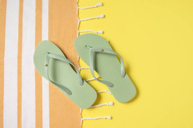 Sarı arka planda battaniyeli yeşil parmak arası terlikler.