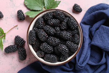 Pembe arka planda olgun böğürtlenli kompozisyon, yakın plan.