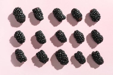 Pembe arka planda taze olgun böğürtlen, yakın plan.