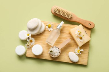 Ahşap tepsi, papatya çiçeği, şişe ve kavanoz dolusu yeşil arka planda kozmetik ürünü, yakın plan