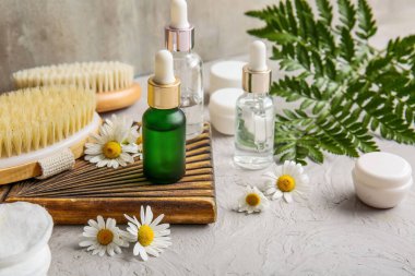 Gri grunge arka planda papatya çiçekleri, kavanozlar ve kozmetik ürünler şişeleri, yakın plan