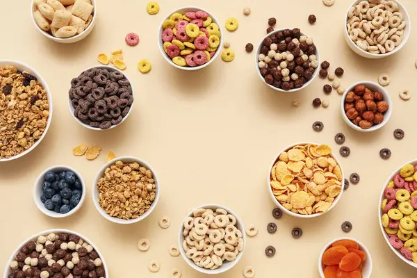 Farklı lezzetli mısır gevrekleri, böğürtlen ve fındıklı bej arkaplanlı kaselerden yapılmış çerçeve.