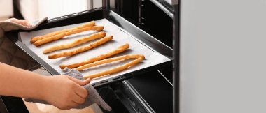 Fırından İtalyan Grissini ile fırın tepsisi çeken kadın.