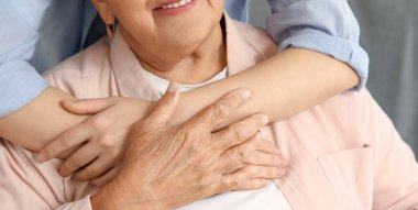 Evde büyükannesine sarılan genç bir kadın.