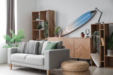 Sörf tahtası, raf ünitesi ve kanepesi olan bir oturma odası.