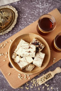 Lezzetli mermer helva parçaları ve arkaplanda Türk çayı olan bardaklar.