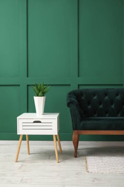 Oturma odasının içinde yeşil kanepe ve masa var.