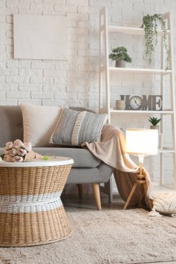 Oturma odasının içi rahat gri kanepe ve parlayan lambayla dolu.