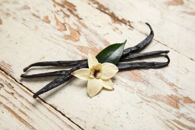 Beyaz ahşap zemin üzerinde Aromatik vanilya çubukları ve çiçek