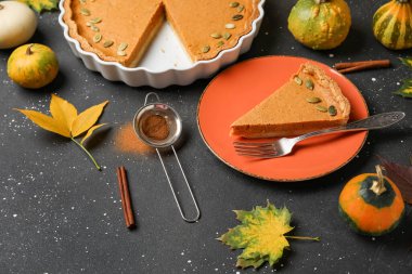 Siyah arka planda lezzetli balkabağı turtasıyla tabak ve fırın.