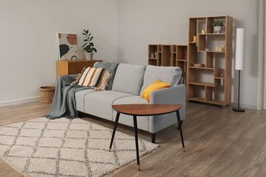 Oturma odasında yerde kahve masası ve halı olan rahat gri kanepe.