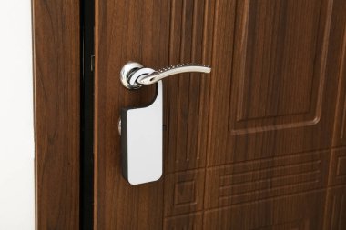 Otel odasında kapı askısı olan siyah ahşap bir kapı.