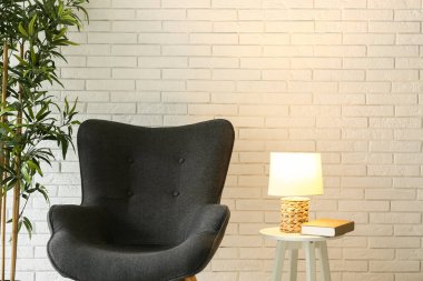 Masada parlayan lamba ve beyaz tuğla duvarın yanında siyah sandalye.