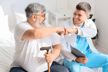 Yatak odasında yumruklaşan yaşlı bir adamla genç bir bakıcı.