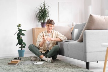 Kitabı olan bir erkek öğrenci evde internette ders çalışıyor.