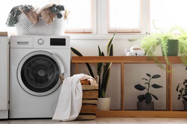 Çamaşır sepetinin içinde kirli çamaşırlar ve banyo içinde çamaşır makinesi.