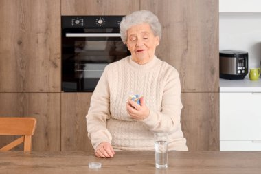 Mutfakta ilaç şişesi olan yaşlı bir kadın.