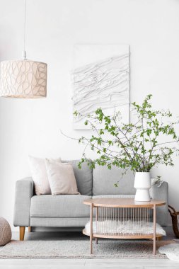 Oturma odasındaki sehpanın üzerinde çiçek açan bir vazo ve rahat bir kanepe.