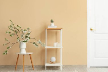 Sehpanın üzerinde, bej odadaki raf ünitesinin yanında çiçek açan bir vazo.