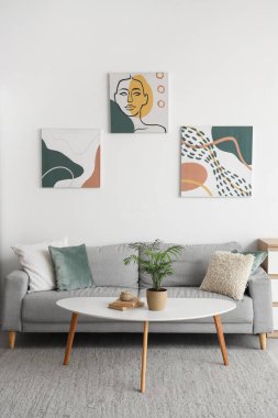 Modern interior of living room with grey sofa and houseplant on table