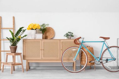 İçinde bisiklet ve ahşap dolapta sarı narsisli çiçekler olan oturma odasının içinde.