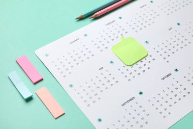 Turkuaz arka planda ofis kırtasiyesiyle takvim