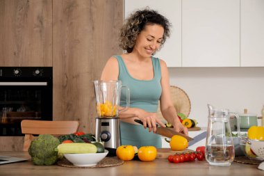 Mutfakta meyve püresi için biber kesen olgun bir kadın.