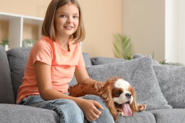 Kral Charles 'ın köpeğiyle oturma odasında kanepede oturan tatlı küçük kız.