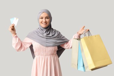 Gri arka planda alışveriş torbaları ve kredi kartları olan tesettürlü güzel Müslüman kadın.