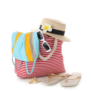 Beyaz arka planda izole edilmiş mayo ve plaj aksesuarları olan çanta, yakın plan.