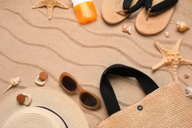 Şık plaj aksesuarları, deniz kabukları ve kumdaki deniz balıklarıyla kompozisyon