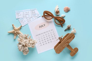 Mavi arka planda güneş gözlüklü, biletli ve deniz kabuklu takvim. Yaz tatili kavramı