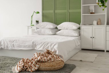 Beyaz çarşaflı, beyaz perdeli ve dolabı olan ışık odasının içinde.