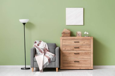 Küp takvimli ahşap çekmeceler, kitaplar, dekor, koltuk ve lamba renkli duvarın yanında.