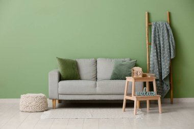 Rahat bir kanepe, merdiven, takvimli masa ve odanın duvarına yakın kitaplar.