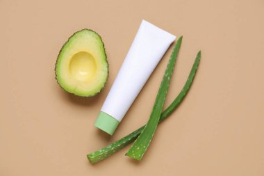 Doğal kozmetik ürün tüpü, aloe yaprakları ve renk arkaplanında avokado