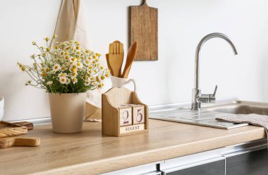 25 Ağustos tarihli küp takvimi ve mutfak tezgahında papatya çayı.