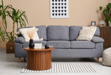 Masasında kanepe, palmiye ağaçları ve küp takvimi olan bir oturma odası.