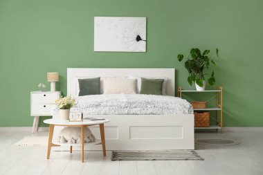 Yatak odasının içinde masalar ve raf ünitesi var.