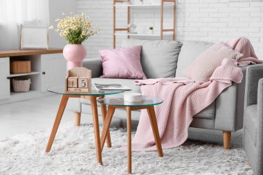 Oturma odasının içinde kanepe, masa ve küp takvimi var.