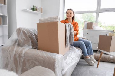 Odadaki koltukta oturan taşınma kutusuyla genç bir kadın.